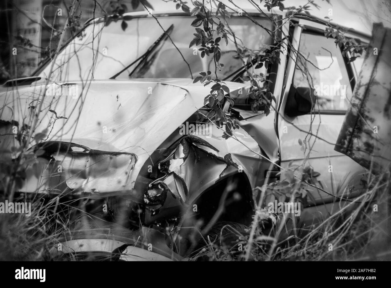 Photo of damaged and rusty car after crash, black and white. Stock Photo