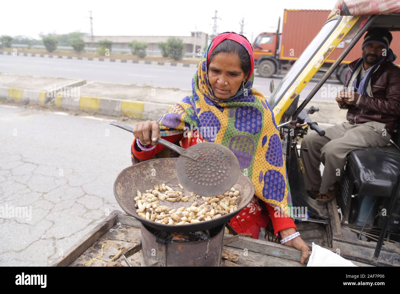 Peanut vendor roasting peanuts during smog in a cold day at Beawar