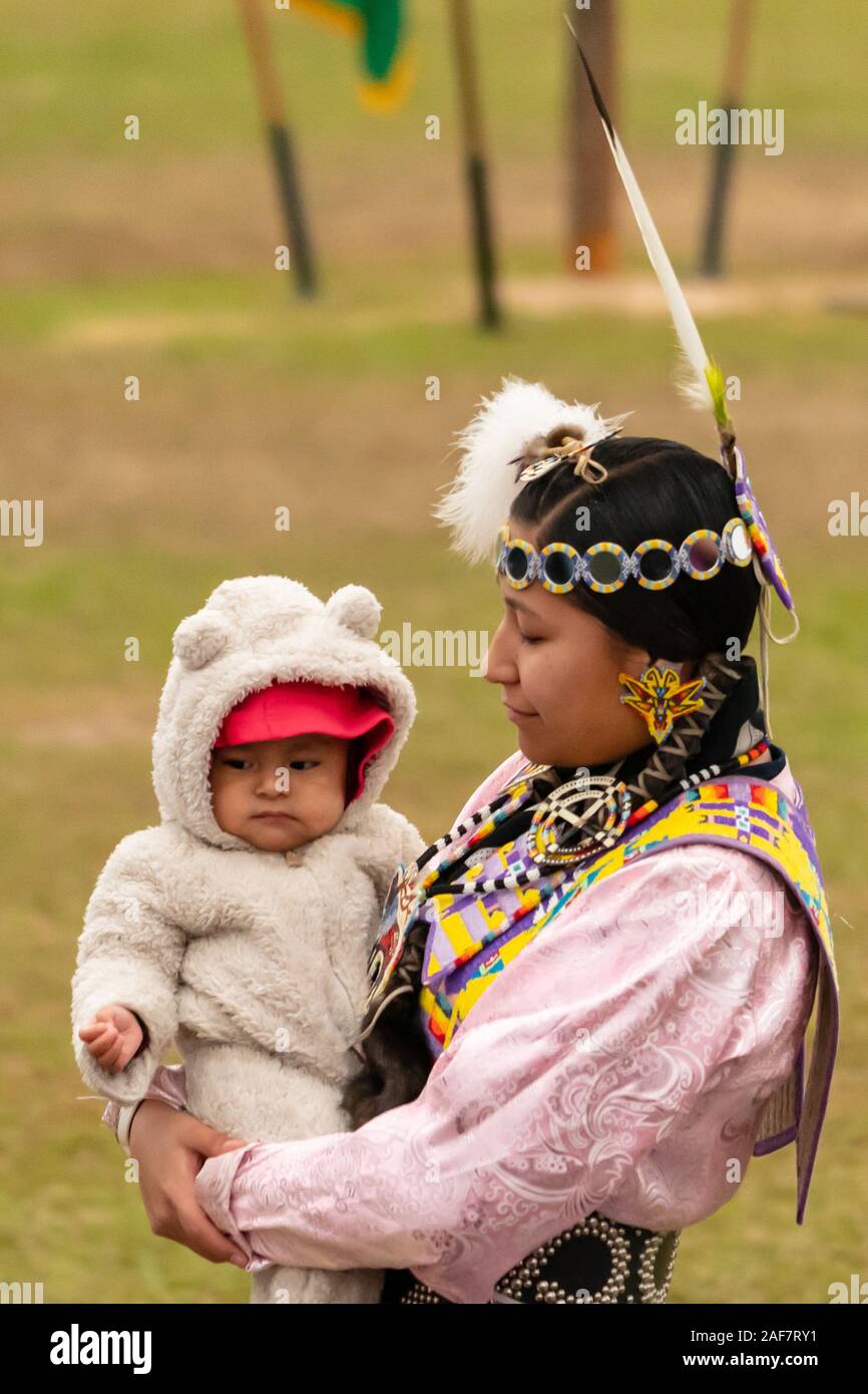 A woman in traditional dress holds a baby at the Poarch Creek Indian Thanksgiving Pow Wow Stock Photo