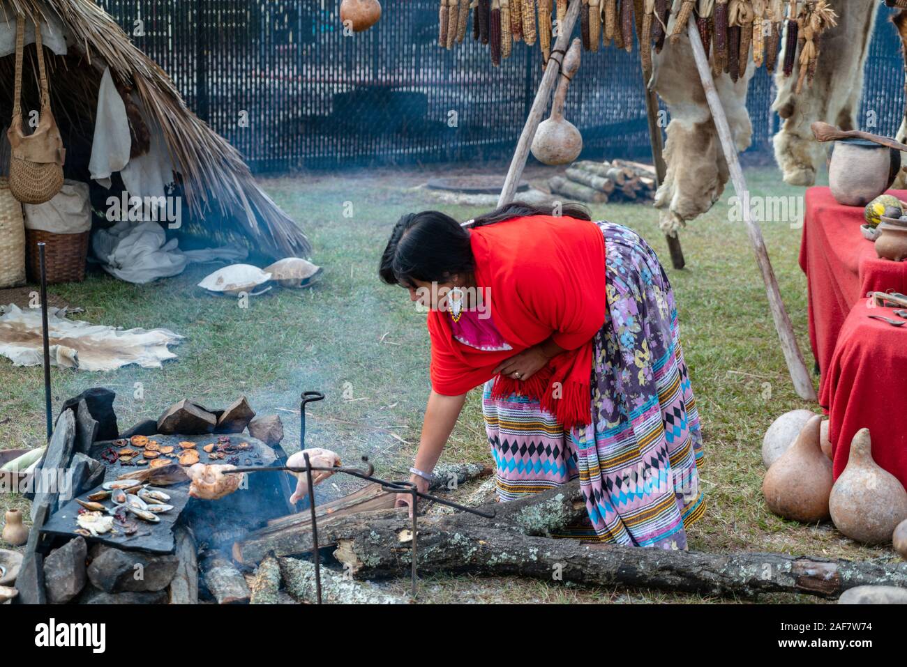 A woman in traditional dress cooks chicken on a fire at the Poarch Creek Indian Thanksgiving Pow Wow Stock Photo