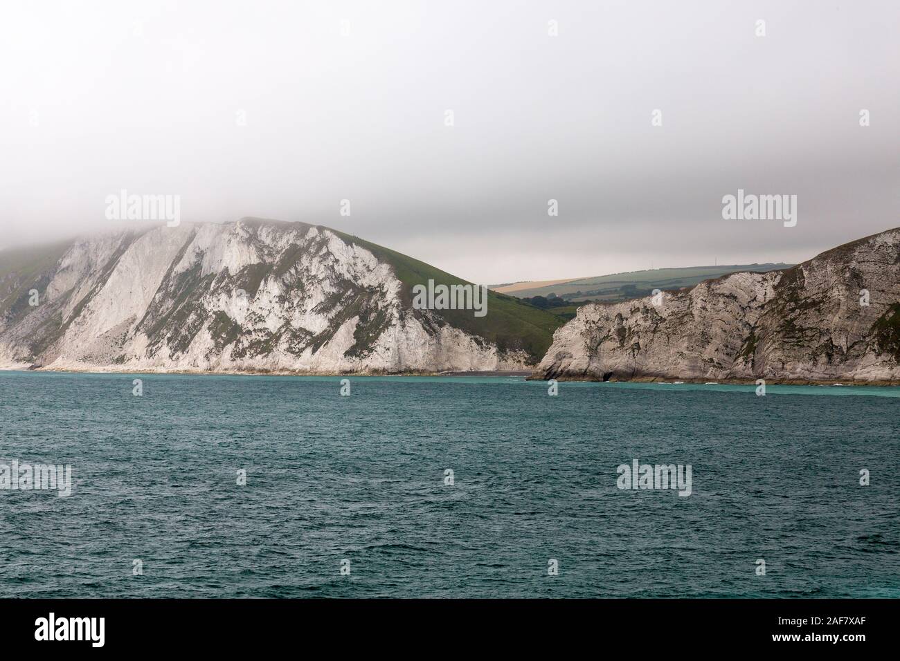 Low cloud covers the tops of the surrounding chalk cliffs in Worbarrow Bay near Tyneham, Dorset, England, UK Stock Photo