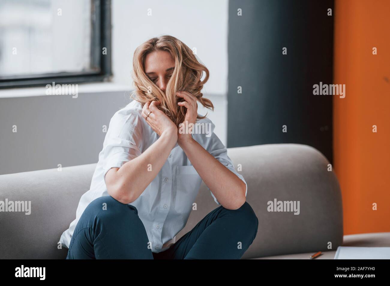 Playful mood. Businesswoman with curly blonde hair sitting in room against window Stock Photo