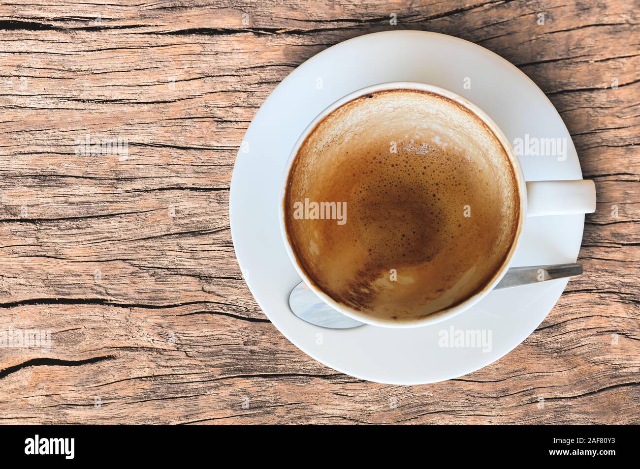 Empty coffee cup after drink foam in white cup on old wooden table Stock Photo