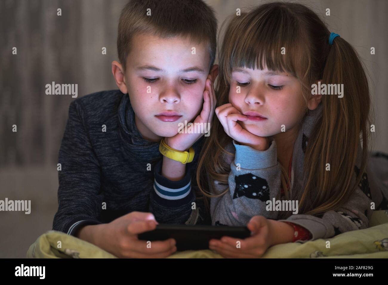 Two children brother and sister watching video on smartphone screen together. Stock Photo