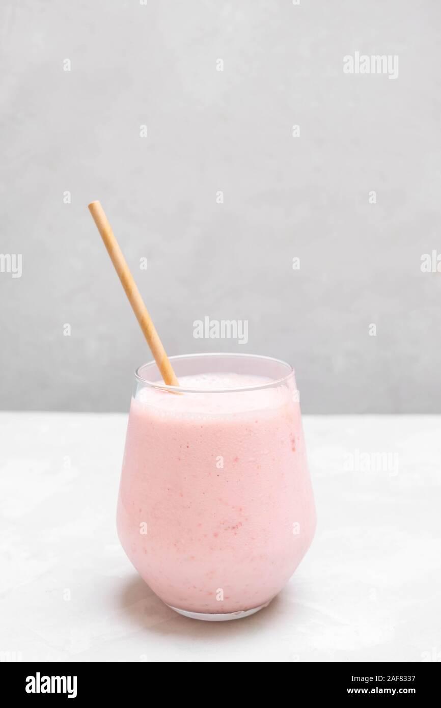 Glass cup of indian drink Strawberry Lassi on grey background with