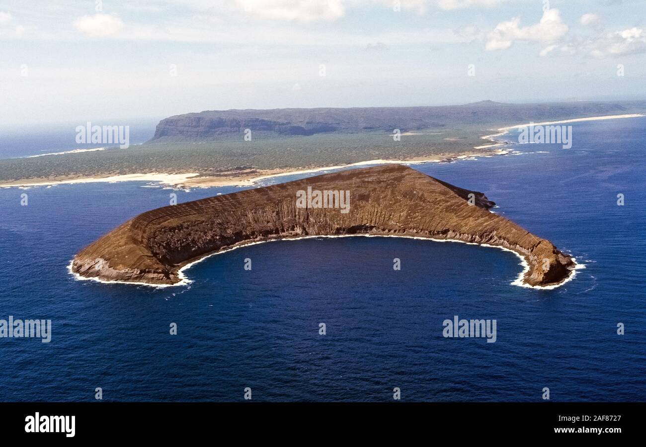 Crescent-shaped Lehua Island is the remnant of an uninhabited extinct volcano and serves as a Pacific Ocean sanctuary for seabirds and marine life in the Hawaiian Islands, USA. Lehau is nearby Niihau (seen in the background), which is known as the Forbidden Island because only Niihauans born on the island are permitted to live there and tourists are limited to a helicopter excursion to visit its shores for only a few hours. Lehau Island is one of the best places to view Hawaii's underwater world; all-day snorkeling trips aboard catamaran tour boats depart daily from the nearby island of Kauai. Stock Photo