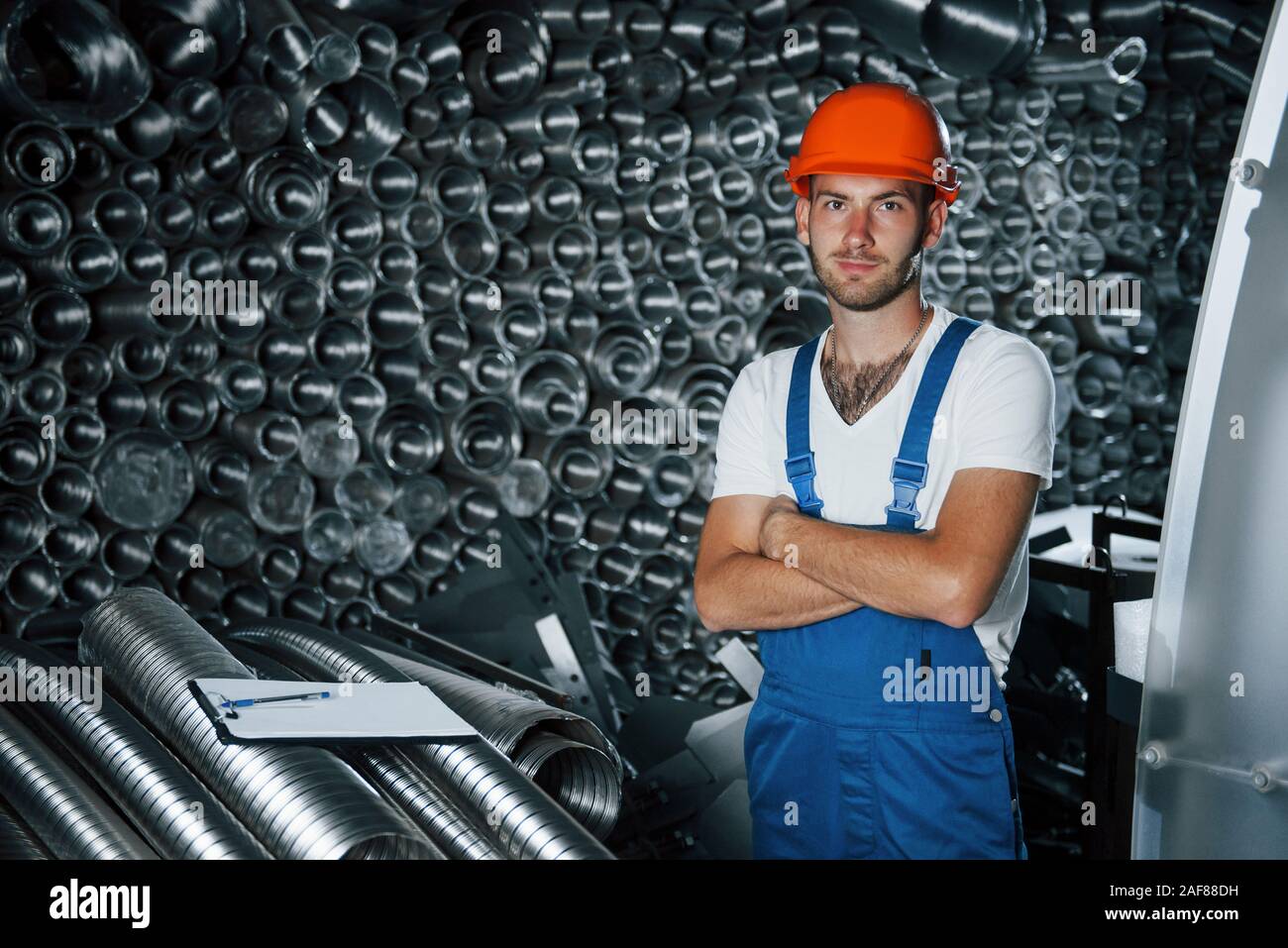 Stands with arms crossed. Man in uniform works on the production