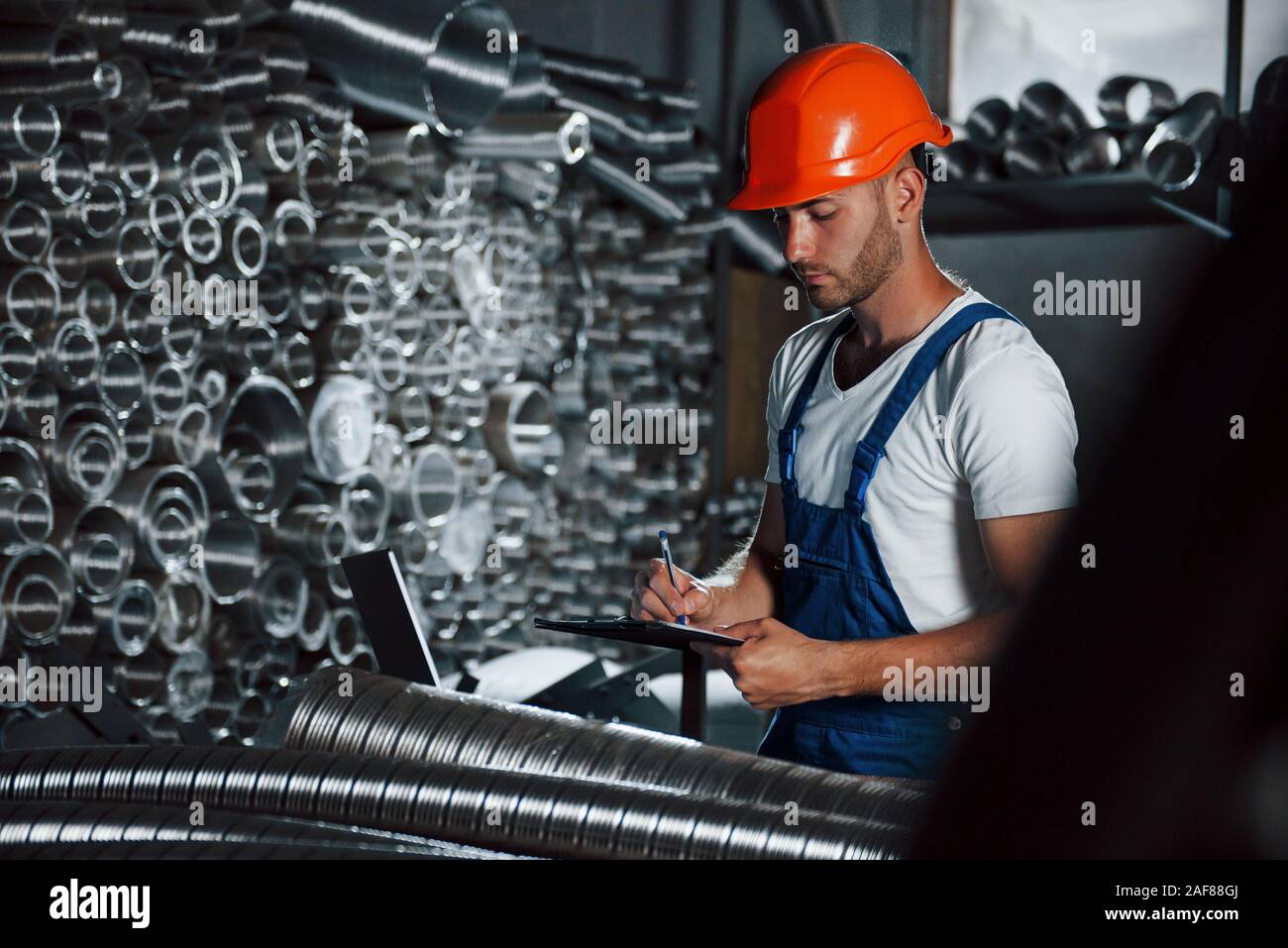 Wrtining in notepad. Man in uniform works on the production. Industrial ...