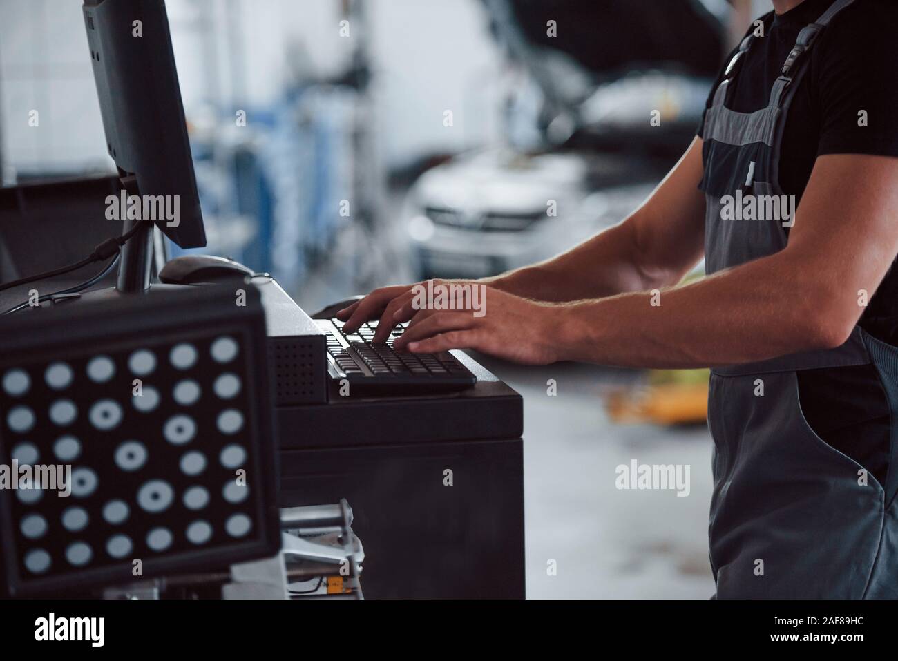 Keyboard, mouse, hands. Man at the workshop in uniform use computer for ...