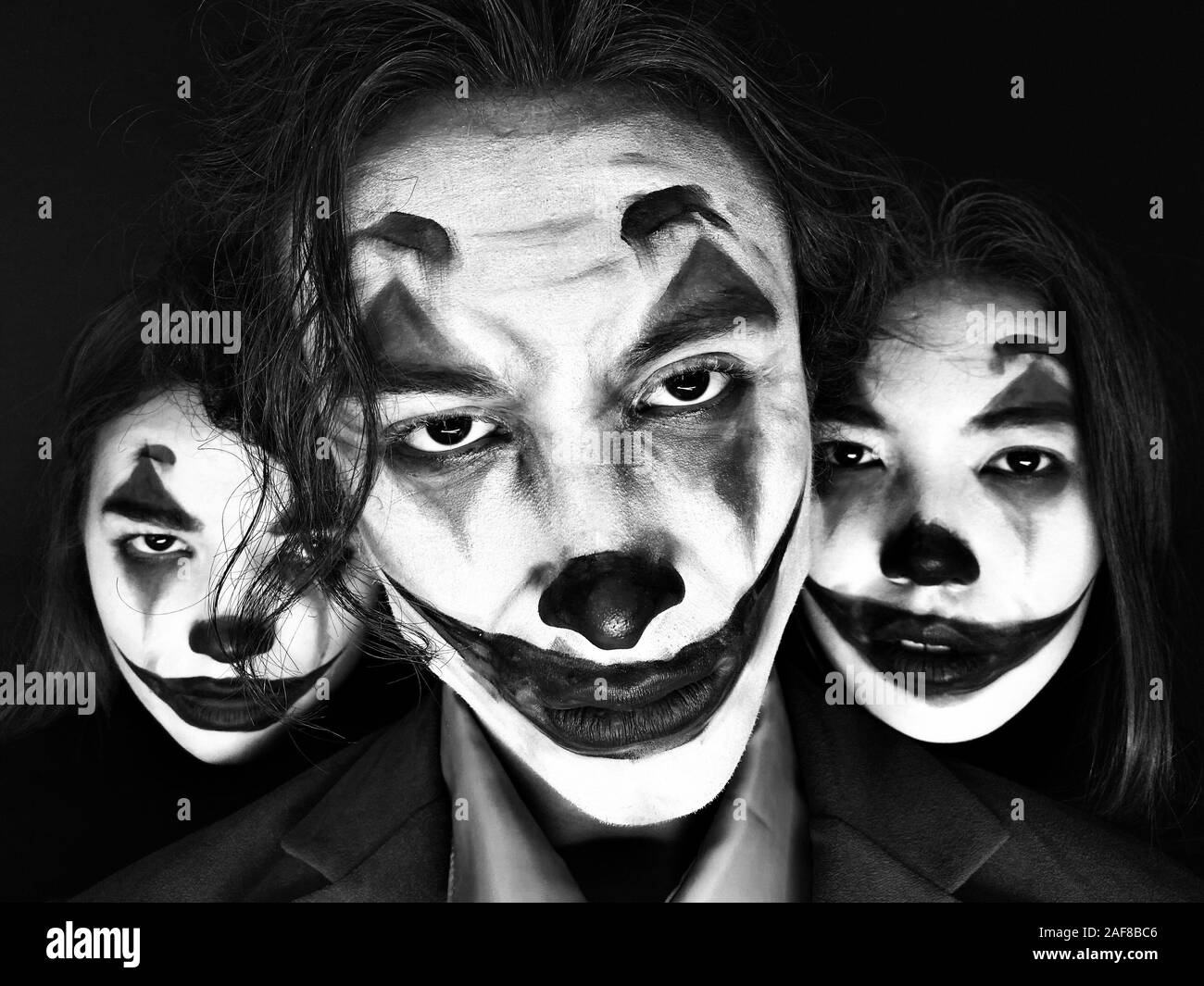 Portrait of three people with clown makeup on a black background. Stock Photo