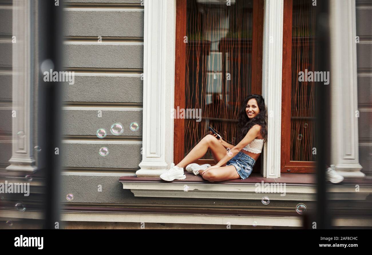 Bubbles is in the air. Beautiful woman with curly black hair have good time in the city at daytime Stock Photo