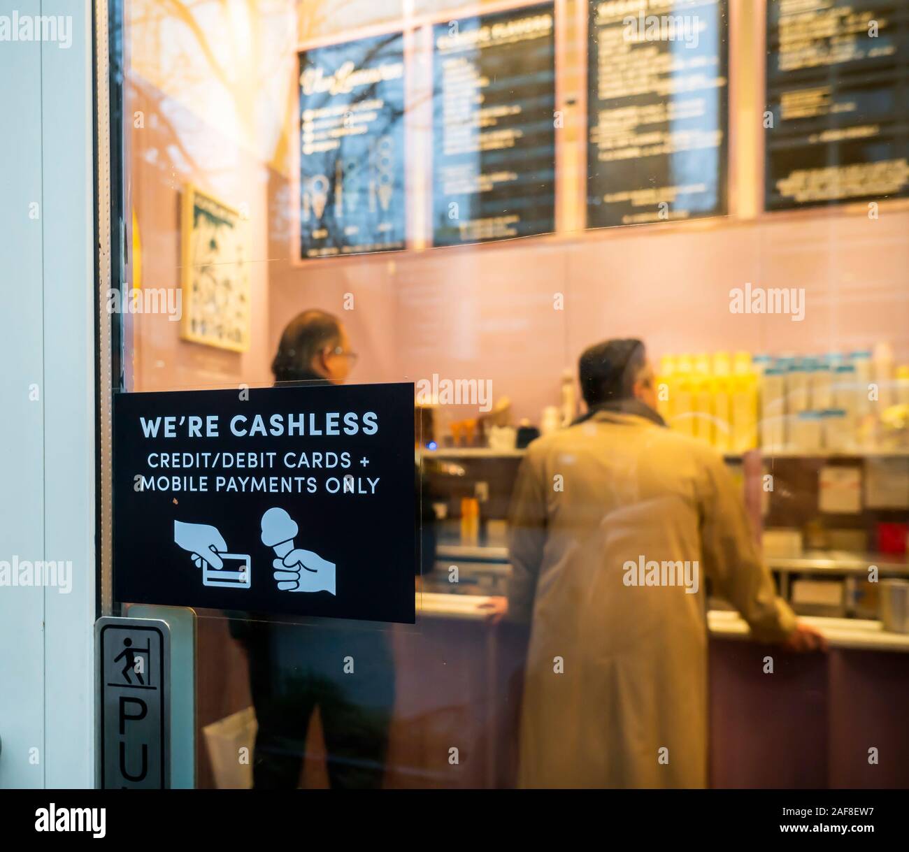 A sign on the door of a Van Leeuwen ice cream parlor in New York informs potential diners that the establishment does not accept cash, only debit and credit cards, seen on Tuesday, December 10, 2019. (© Richard B. Levine) Stock Photo