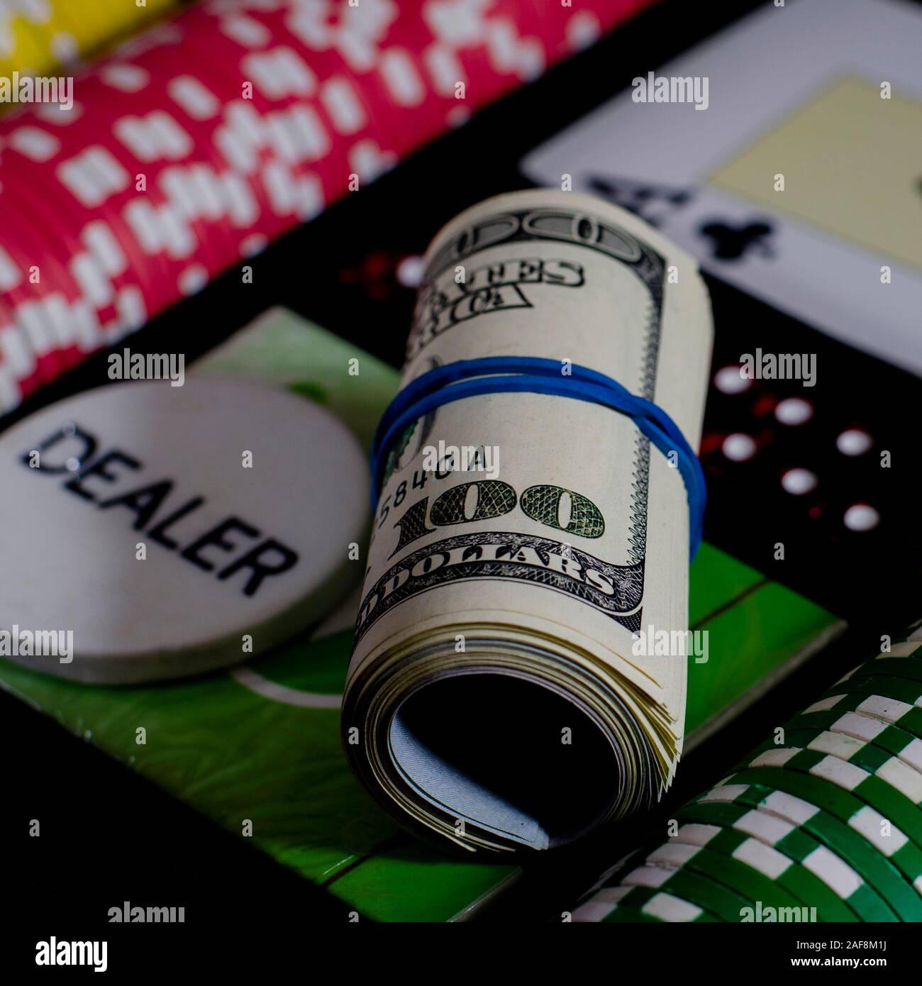 A 100 dollar kupurs is on the blackjack table next to poker chips and a dealer's chip Stock Photo