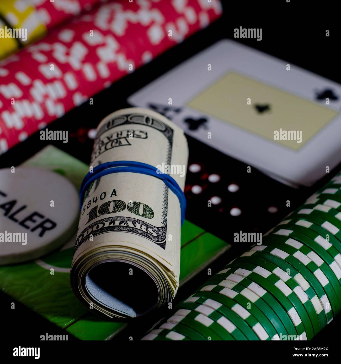 A 100 dollar kupurs is on the blackjack table next to poker chips and a dealer's chip Stock Photo