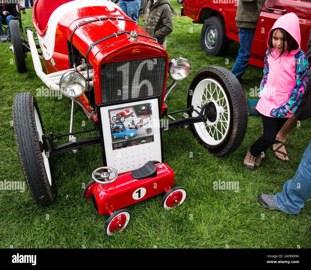 A restored stock Ford 1916 Model T Indianapolis 500 racer in the Moab April Action Car Show in Moab, Utah.  A little girl looks at the vintage toy car Stock Photo
