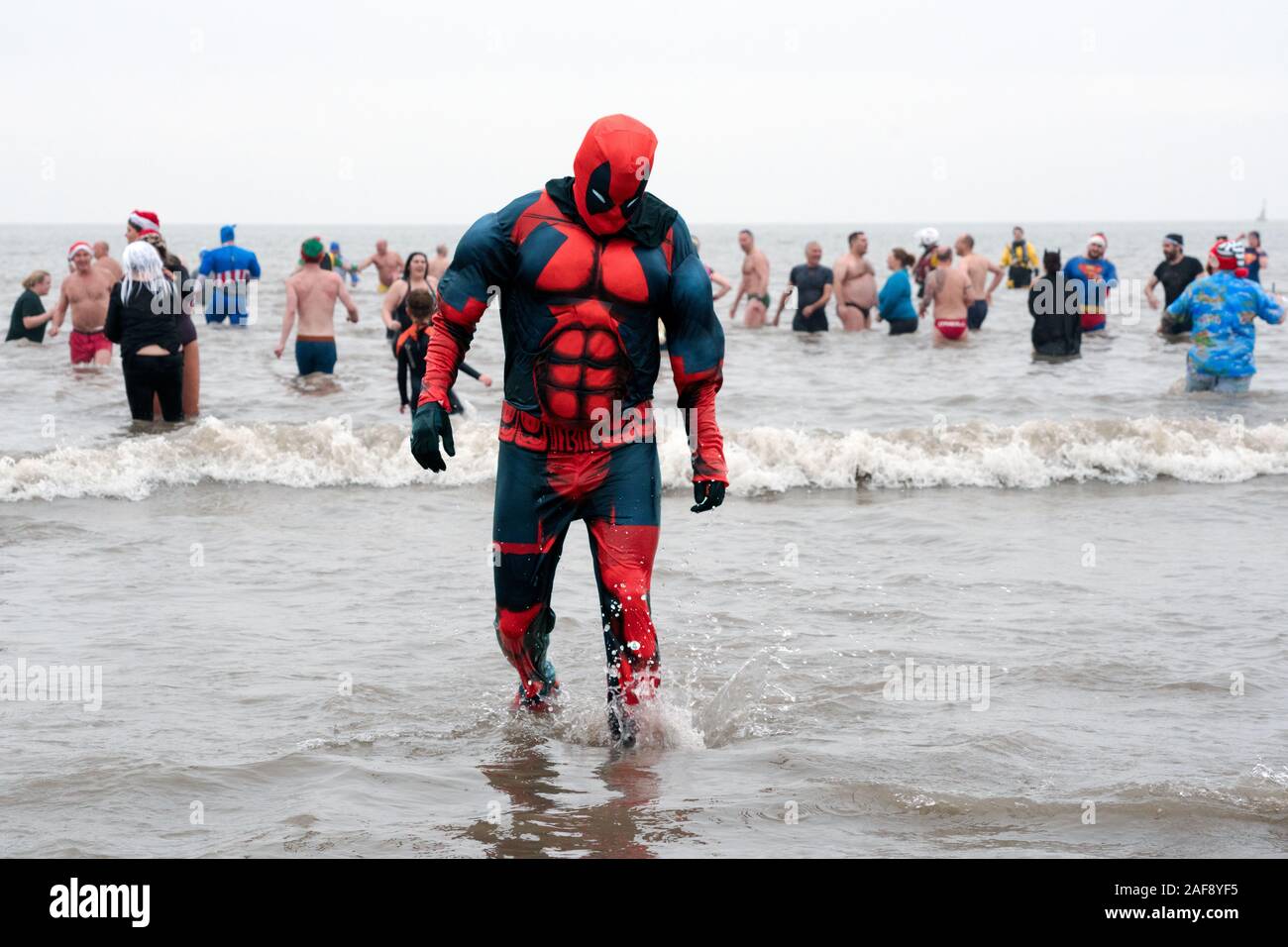 Christmas Day fancy dress charity swim in Porthcawl, a seaside town in South Wales. Super Hero wearing Spiderman Costume emerging from sea. 25-12-2018 Stock Photo