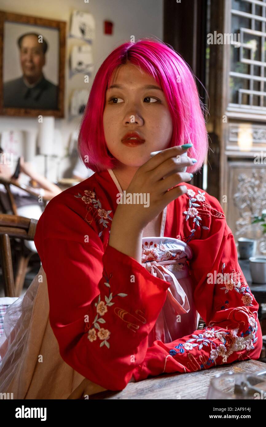 A fashionable young Chinese woman drinking tea and wearing a traditional Chinese tunic Stock Photo