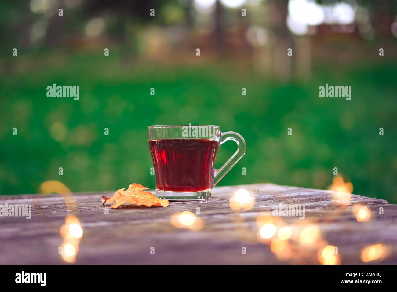 Cozy autumn tea break with a cup of tea , sunglasses, and dry autumn leaves on old vintage wooden table. top down view. Stock Photo