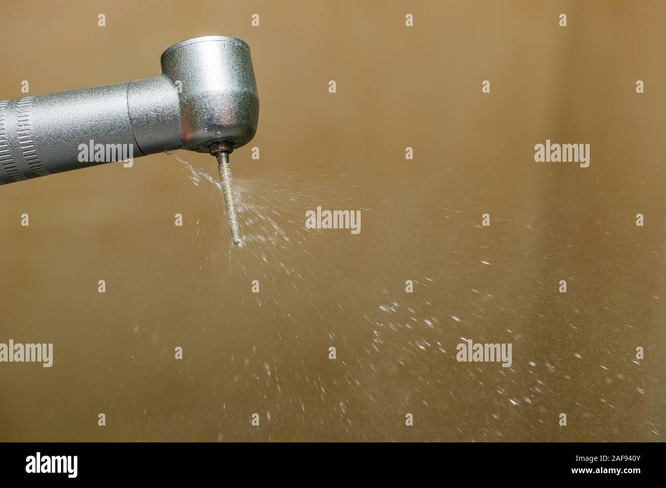 Dental handpiece with a diamond bur and a stream of water cooling the