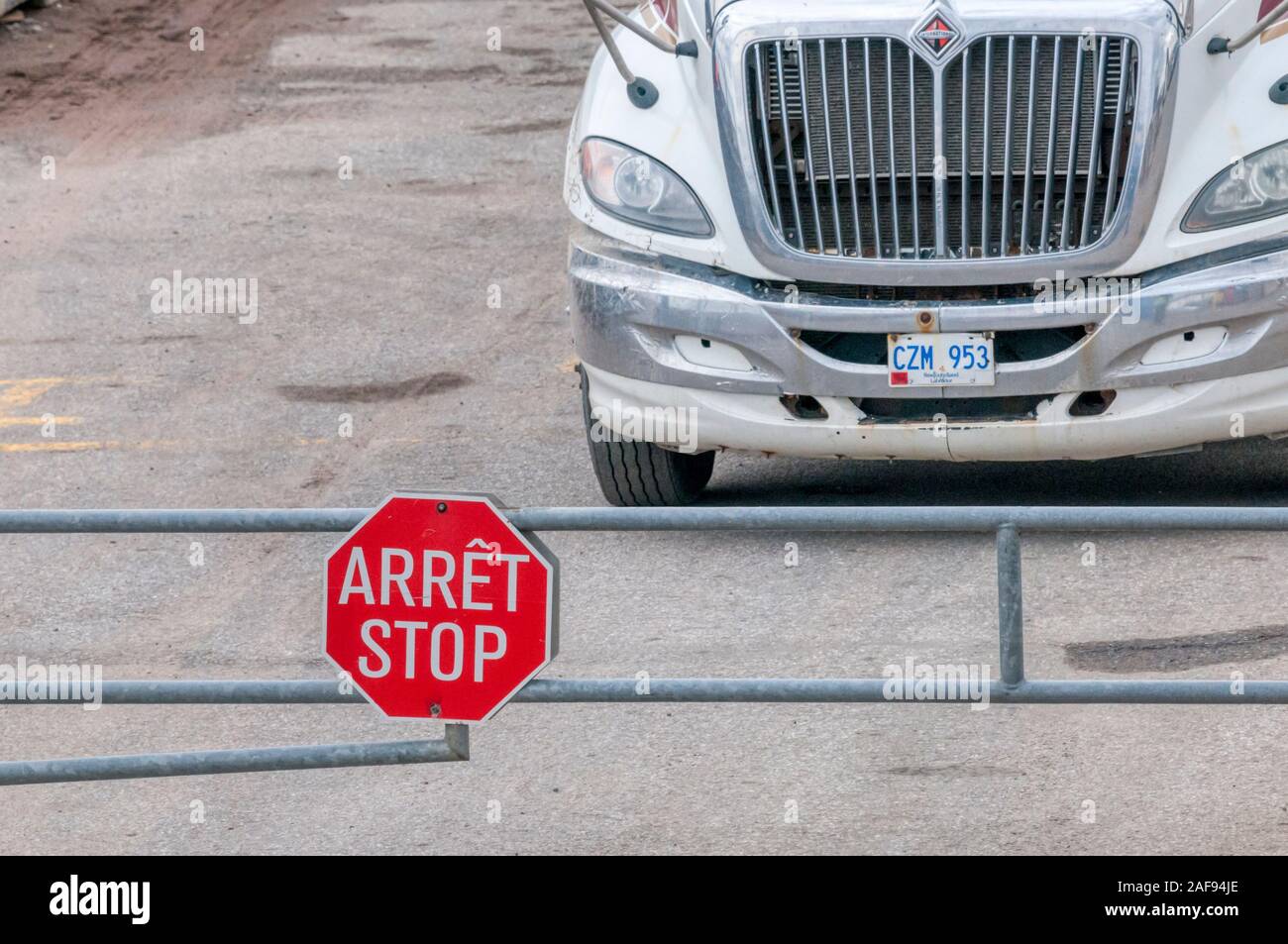 Truck stopped behind bilingual Arret / Stop sign in Blanc-Sablon in Quebec, Canada. Stock Photo