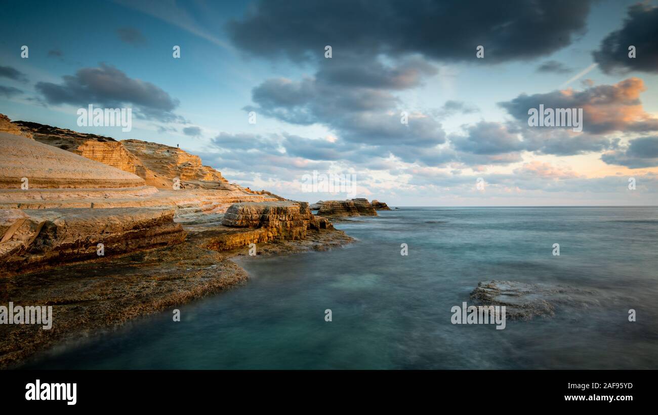 Rocky seashore seascape with wavy ocean and dramatic and beautiful sunset at sea caves coastal area  in Paphos, Cyprus Stock Photo