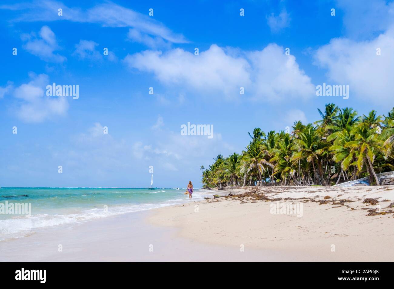 A woman walking along an idyllic tropical beach Stock Photo