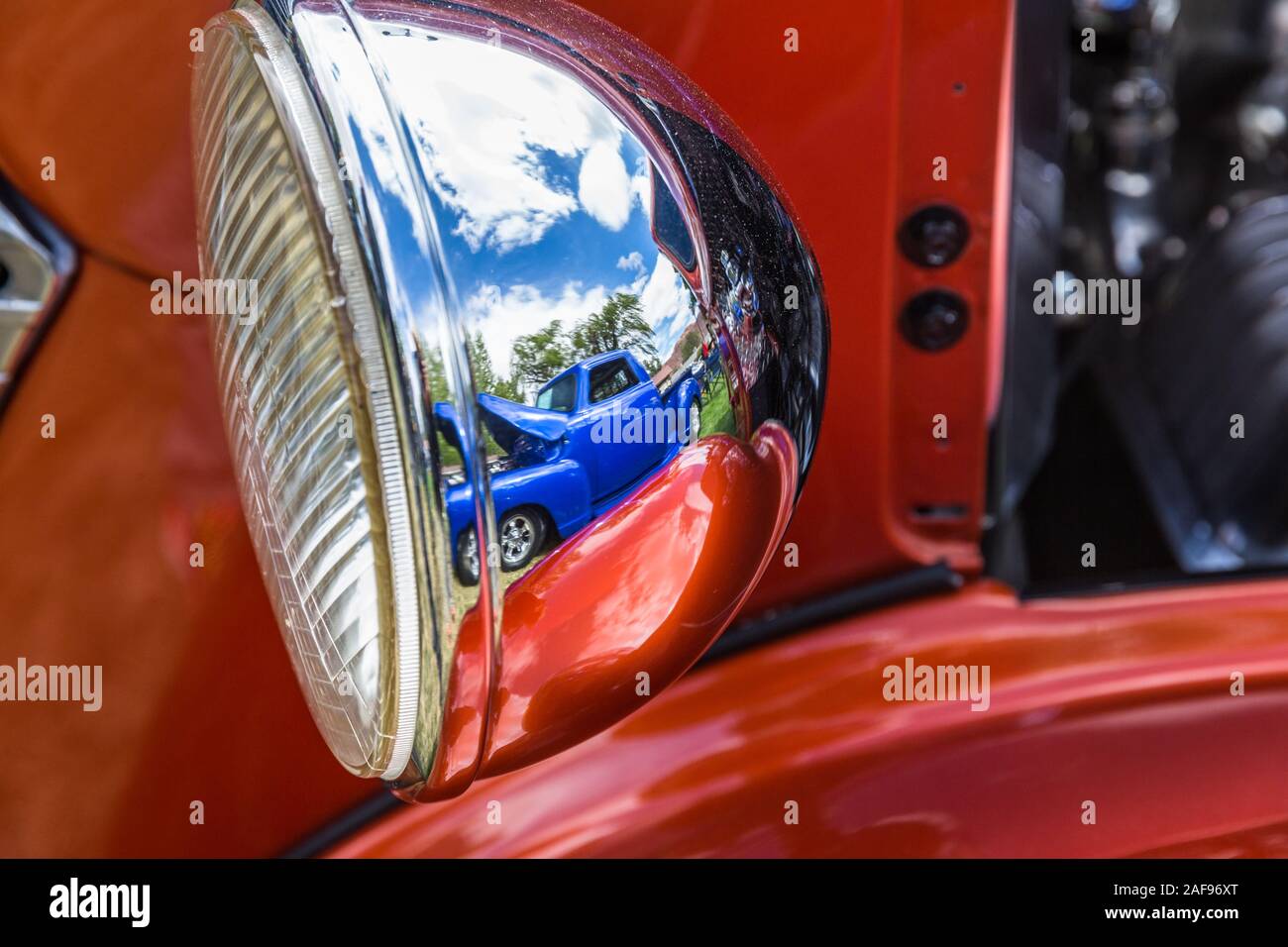 A 1951 Chevy pickup truck is reflected in the chrome headlight of a 1938 Chevy truck in the Moab April Action Car Show in Moab, Utah. Stock Photo