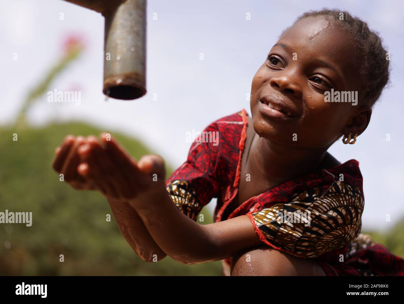 Portrait Image of African Black Girl Drinking Safe Clean Freshwater from Tap (Water for Africa) Stock Photo
