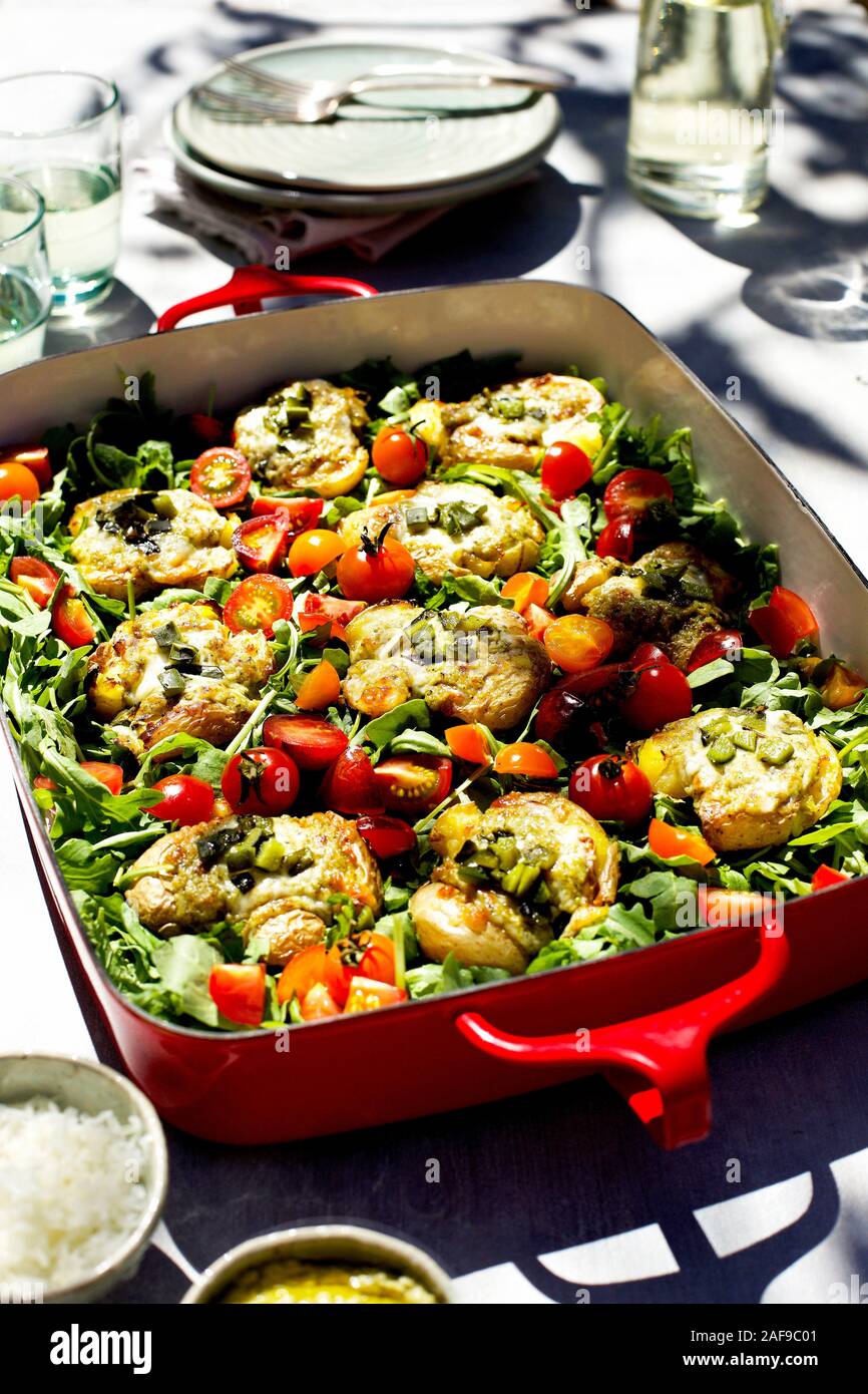 Roasted Poblano Pesto Smashed Potatoes served on a bed of arugula and cherry tomatoes Stock Photo