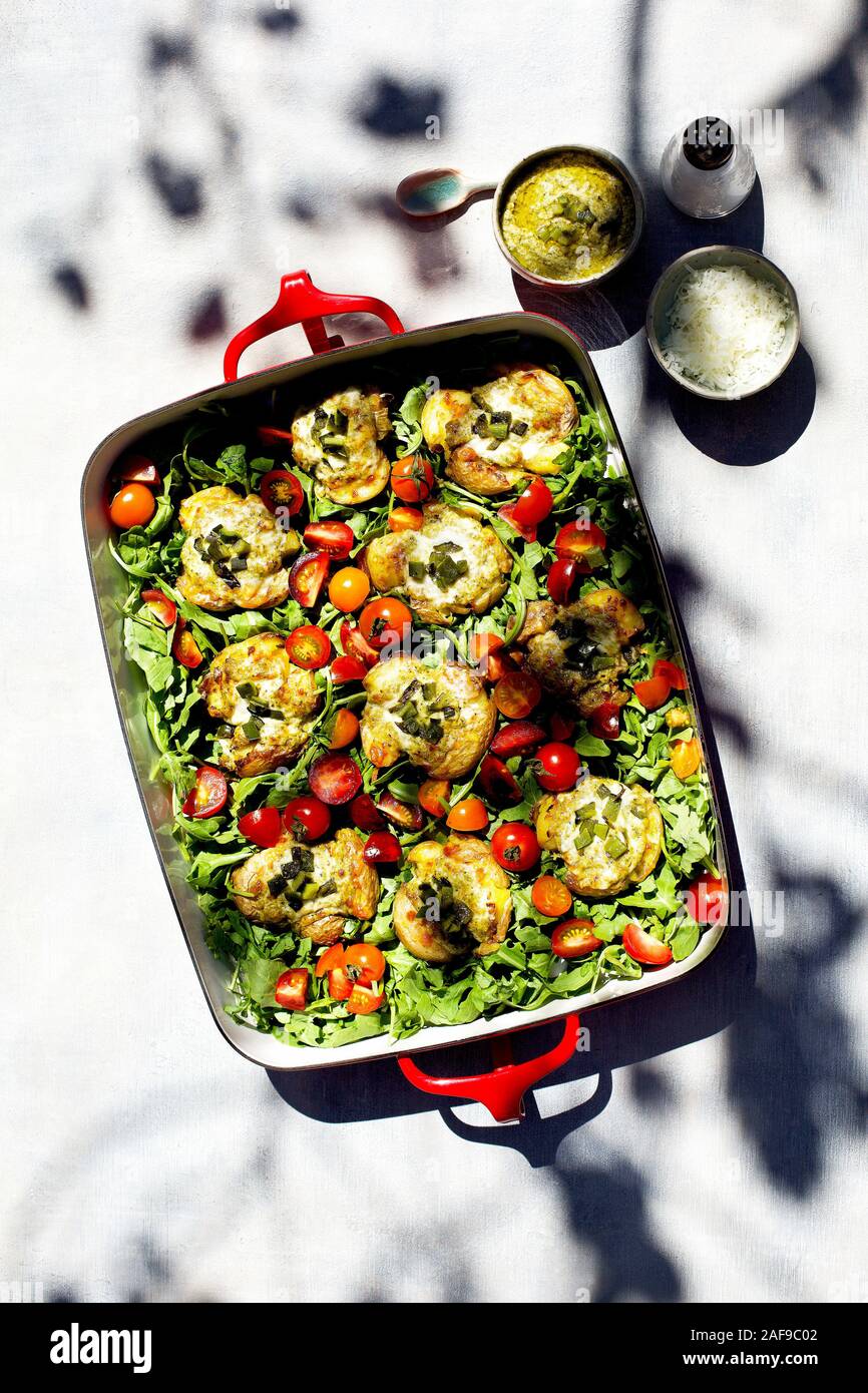 Roasted Poblano Pesto Smashed Potatoes served on a bed of arugula and cherry tomatoes Stock Photo