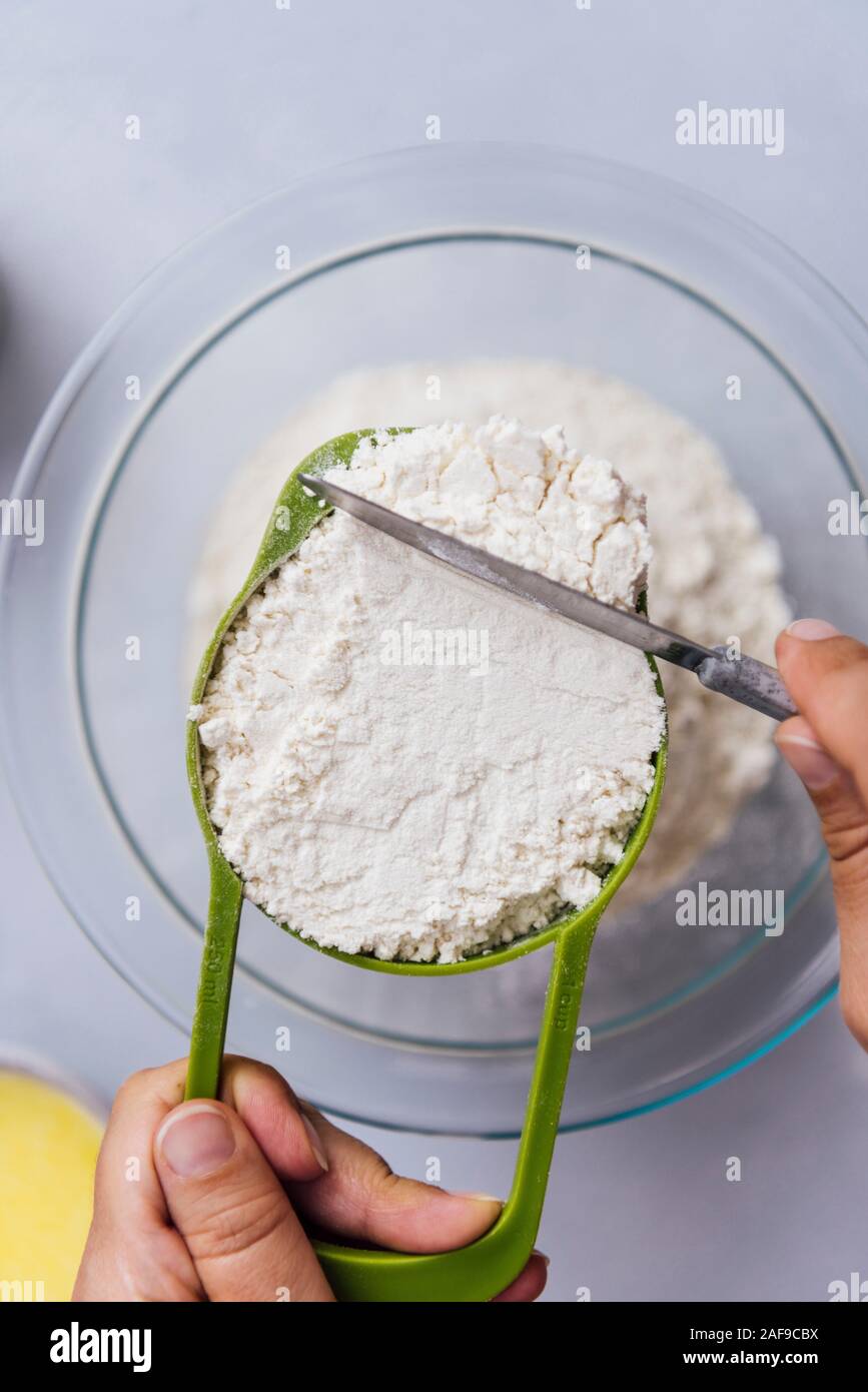 Woman leveling off flour in a measuring cup using a knife Stock Photo Alamy