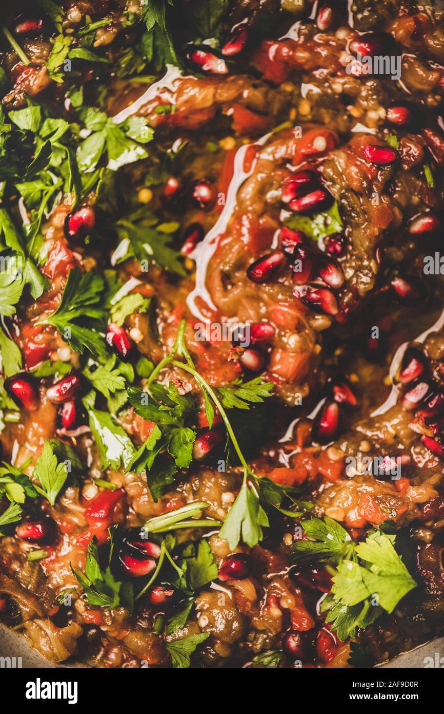 Turkish, Middle East traditional meze starter. Flat-lay of Babaganoush dip seasoned with parsley, lemon and pomegranate seeds, close-up. Oriental typi Stock Photo