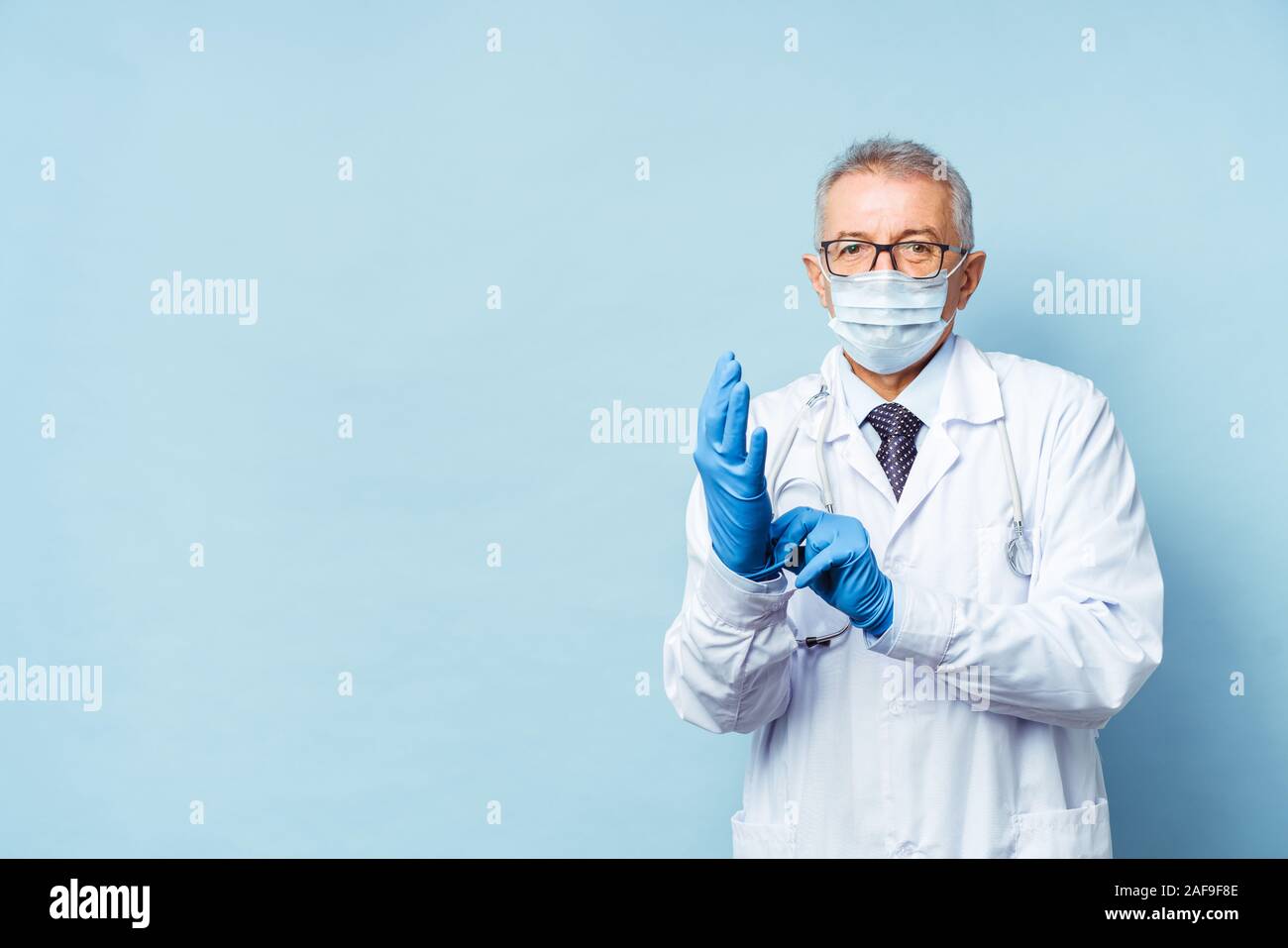 doctor puts on rubber gloves, healthcare and medicine. Isolate on blue background Stock Photo
