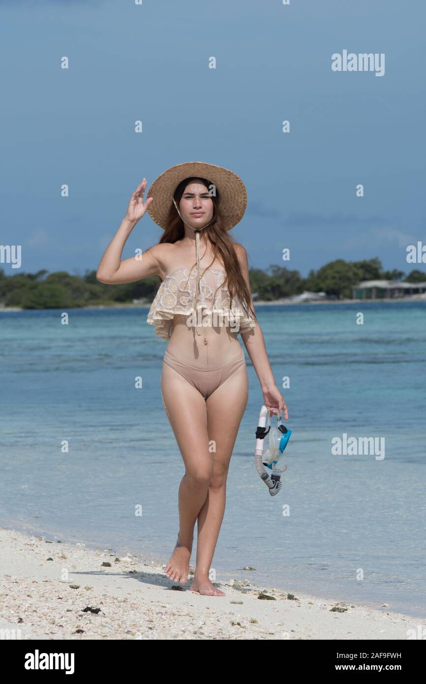 Young woman with wet skin and with a snorkel standing on sand and going to swim in clear sea Stock Photo