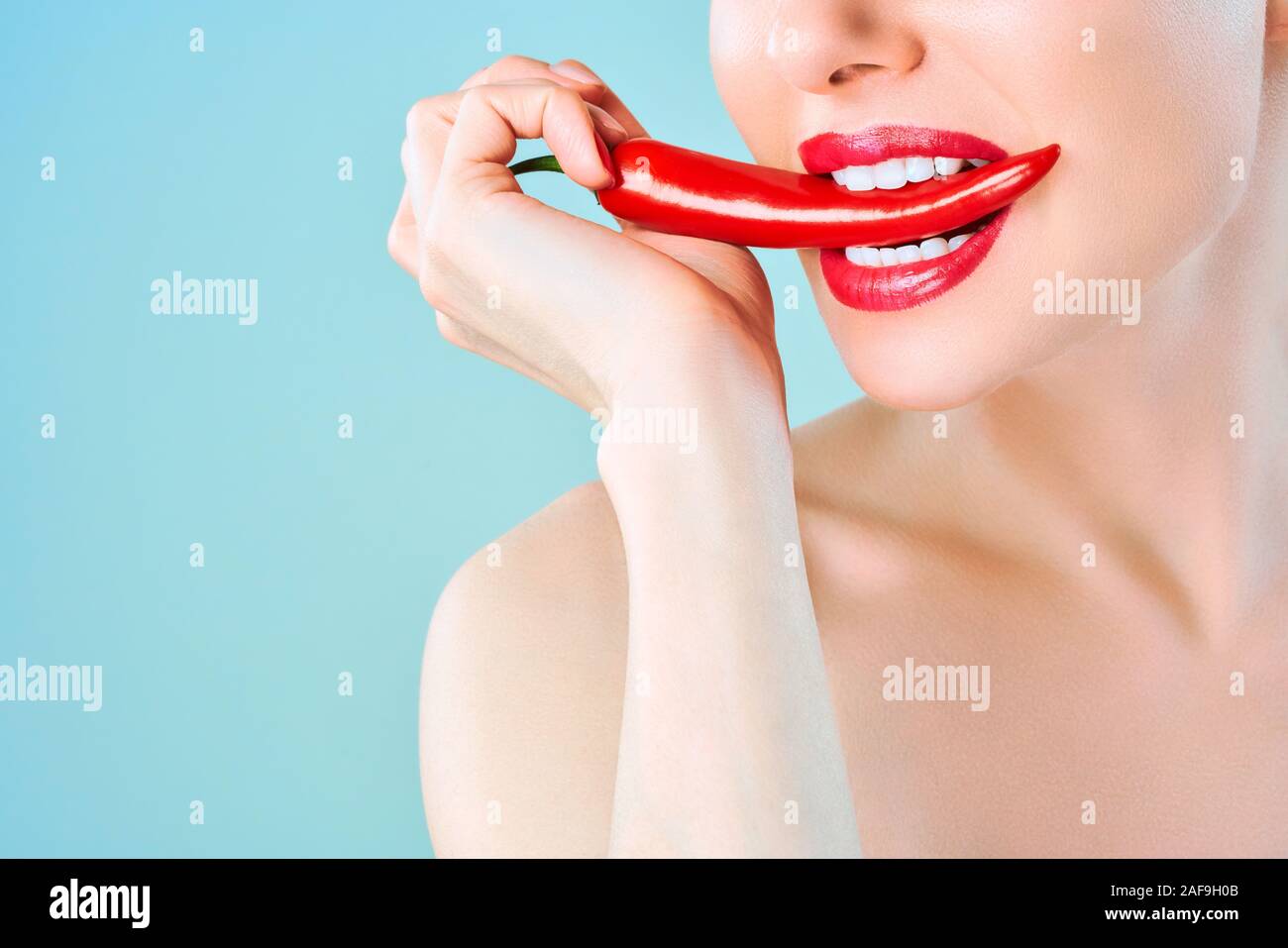 Young woman with chili red pepper isolated en blue background. Sexy female  lips. Hot seductive girl Stock Photo - Alamy