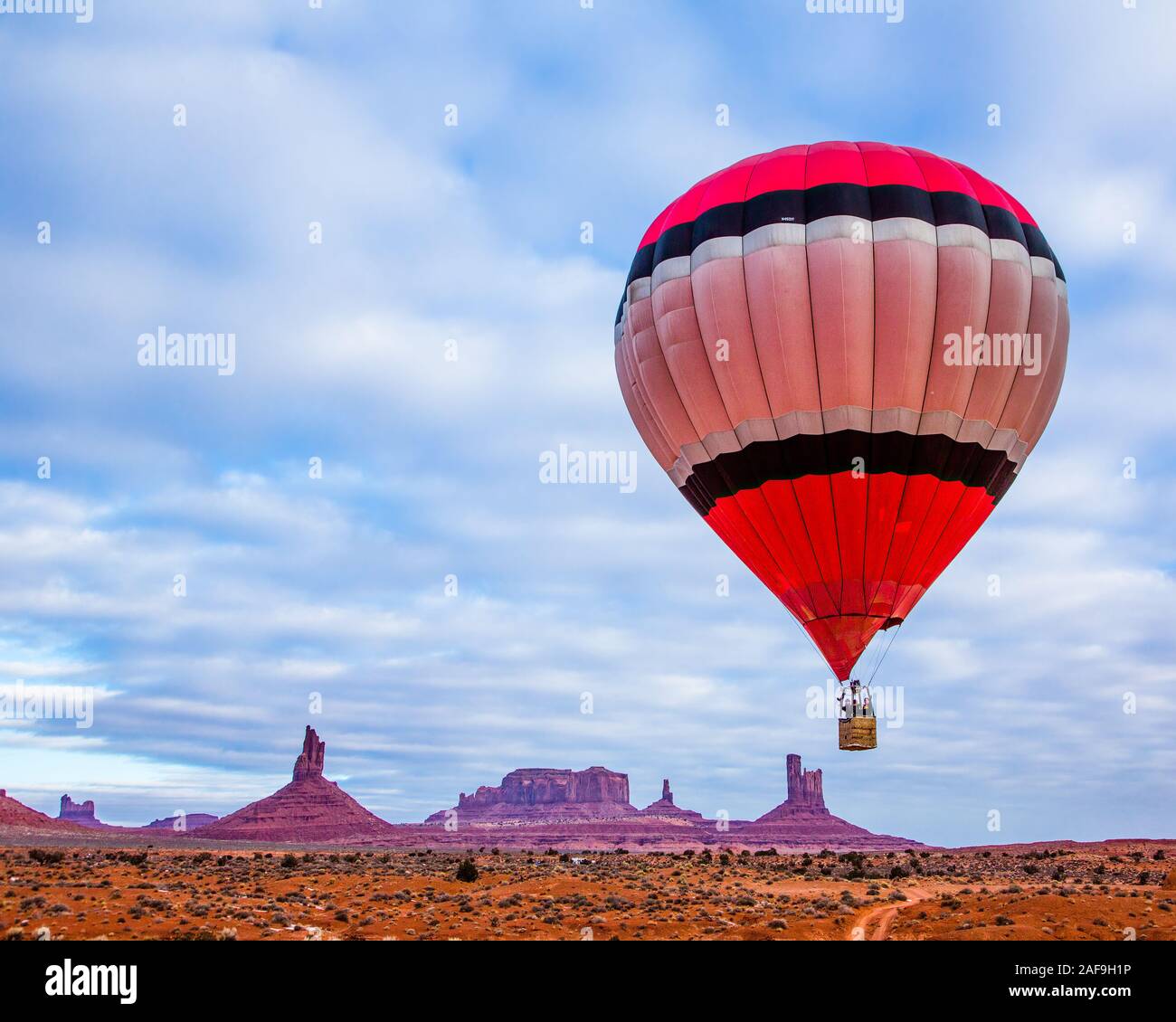 A hot air balloon flying in front of the Utah Monuments in the Monument Valley Balloon Festival in the Monument Valley Navajo Tribal Park in Arizona. Stock Photo