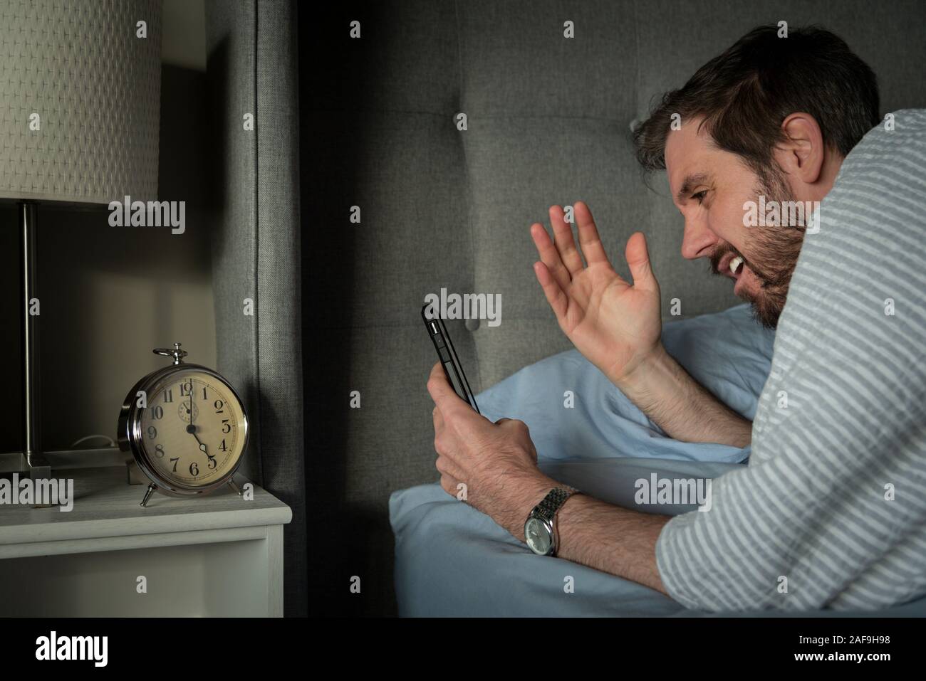 Man reacting to morning news on his smart phone device. Stock Photo