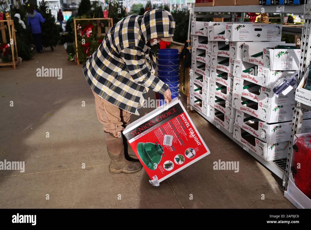 Cromwell, CT USA. Dec 2019. White bearded elderly man in plaid coat looking at new Christmas tree stands in box. Stock Photo