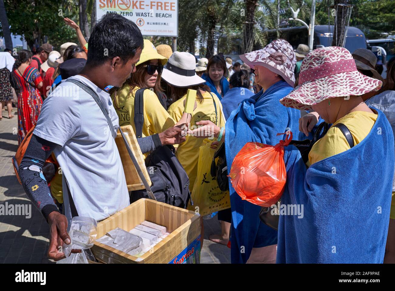 Chinese tourists buying Ice lollies from a street vendor at Pattaya