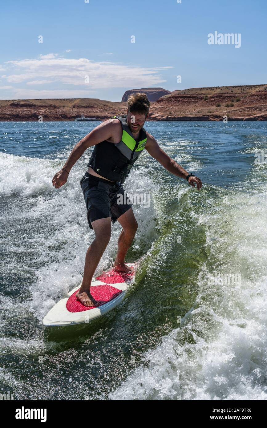 A young man wake surfing behind a boat on Lake Powell in the Glen Canyon National Recreation