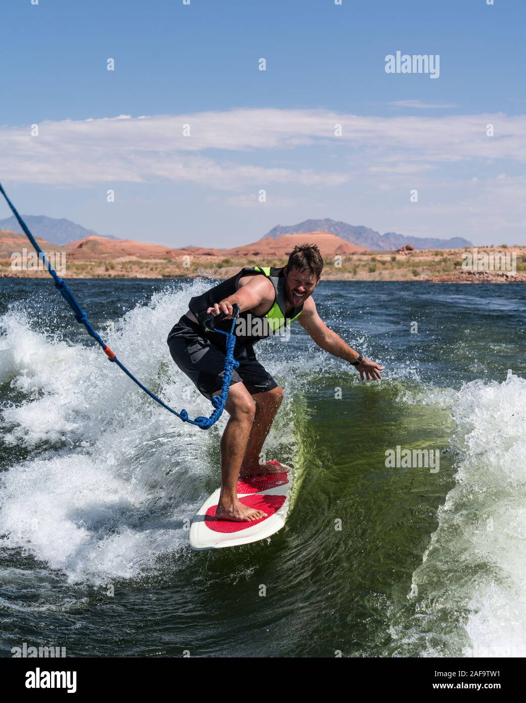 A young man wake surfing behind a boat on Lake Powell in the Glen Canyon National Recreation Area in southern Utah, USA. Stock Photo