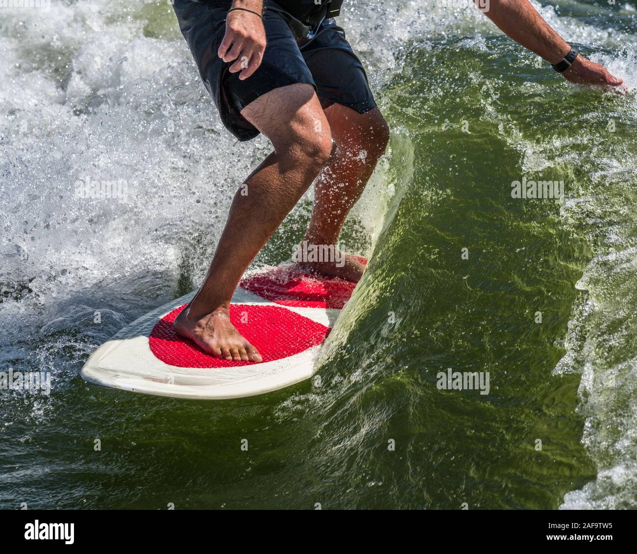 A young man wake surfing behind a boat on Lake Powell in the Glen