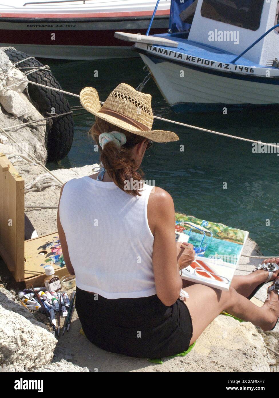 Woman painting a harbour scene at the harbour of Limni Keriou, Zakynthos island, Greece Stock Photo