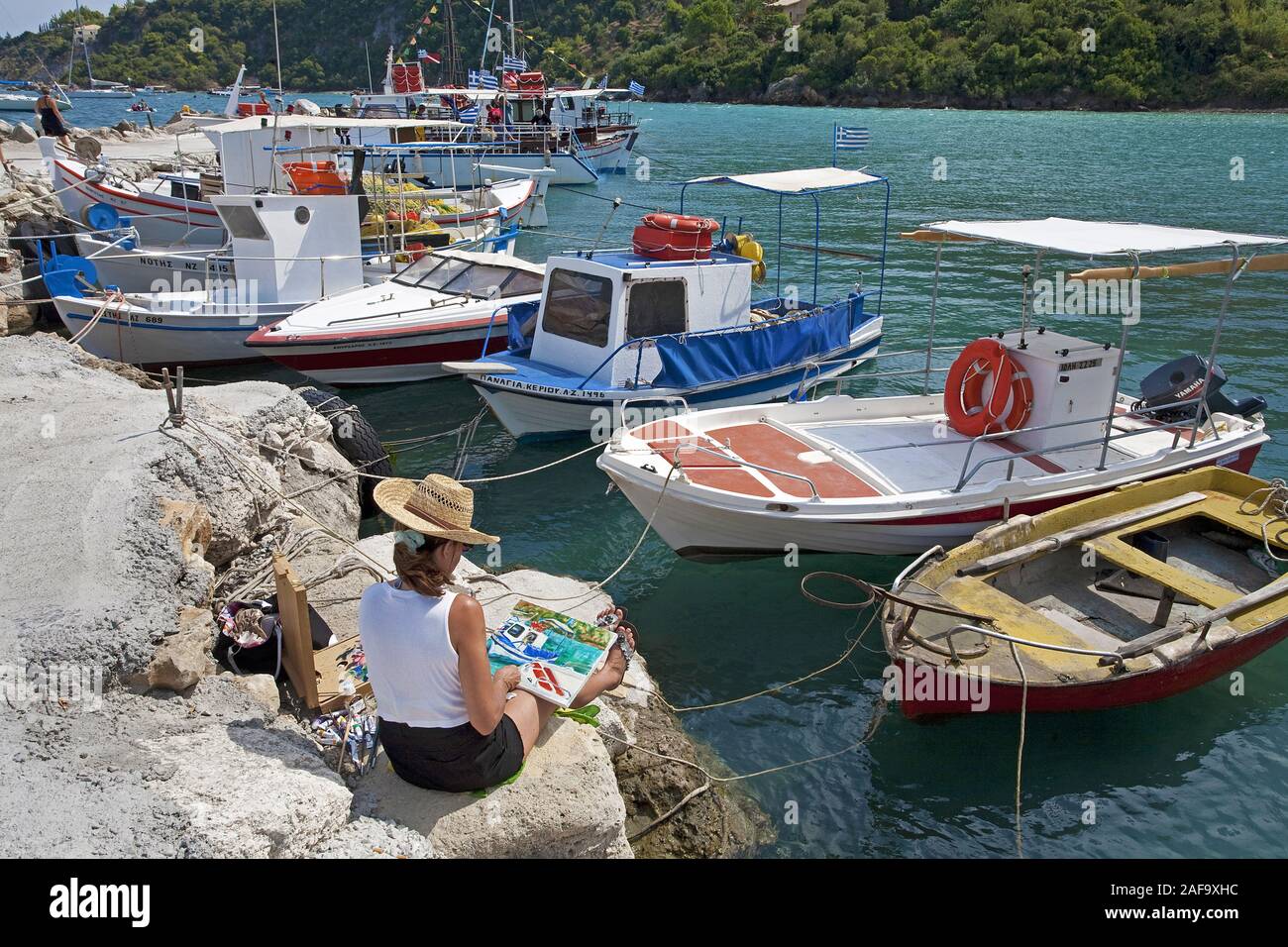 Woman painting a harbour scene at the harbour of Limni Keriou, Zakynthos island, Greece Stock Photo