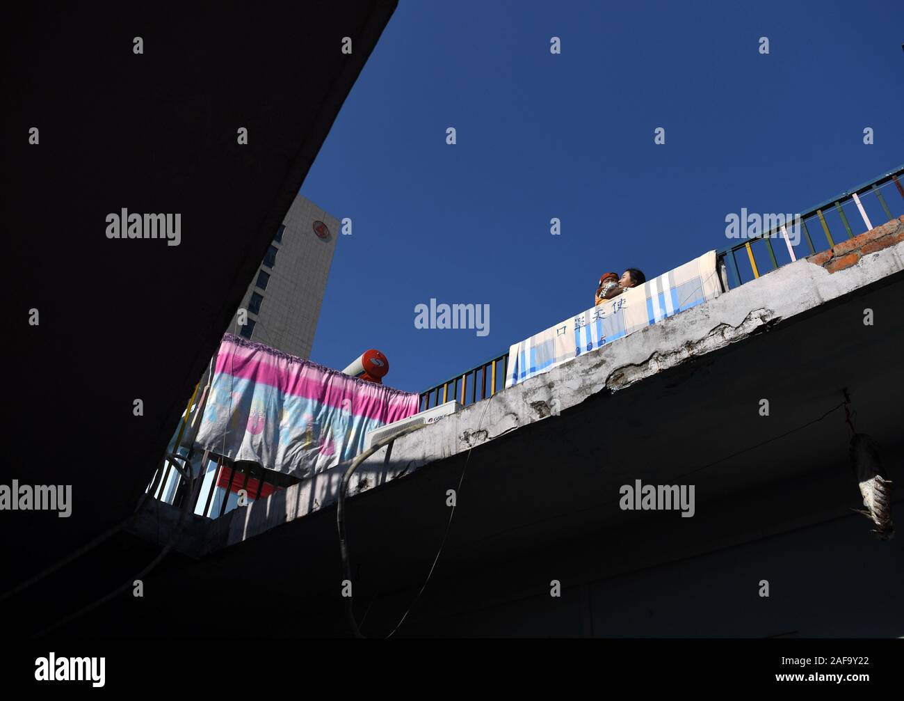 (191214) -- HEFEI, Dec. 14, 2019 (Xinhua) -- A parent and a child are seen on the roof of a hostel near the Children's Hospital in Hefei, east China's Anhui Province, Dec. 9, 2019. Near the Children's Hospital in Hefei, there is a two-story pink building, which is rented by a non-governmental welfare organization as hostel that provides short-term free rooms and self-help 'Love Kitchen' for poverty-stricken families with children seeking medical care. In the 'Love Kitchen', water, electricity, rice, flour, grain, oil and kitchen utensils are all available for free use. In order to make the Stock Photo