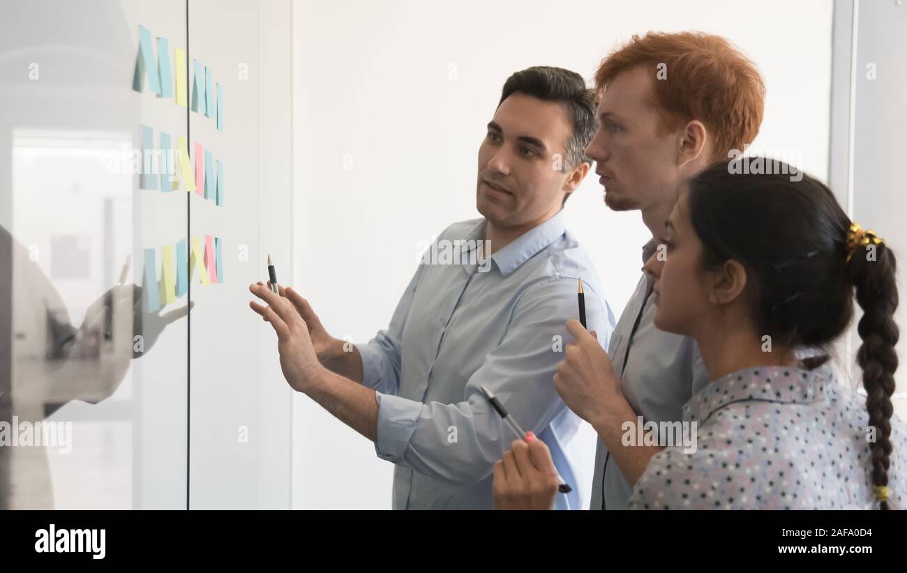 Diverse specialist working together in boardroom using post-it notes Stock Photo