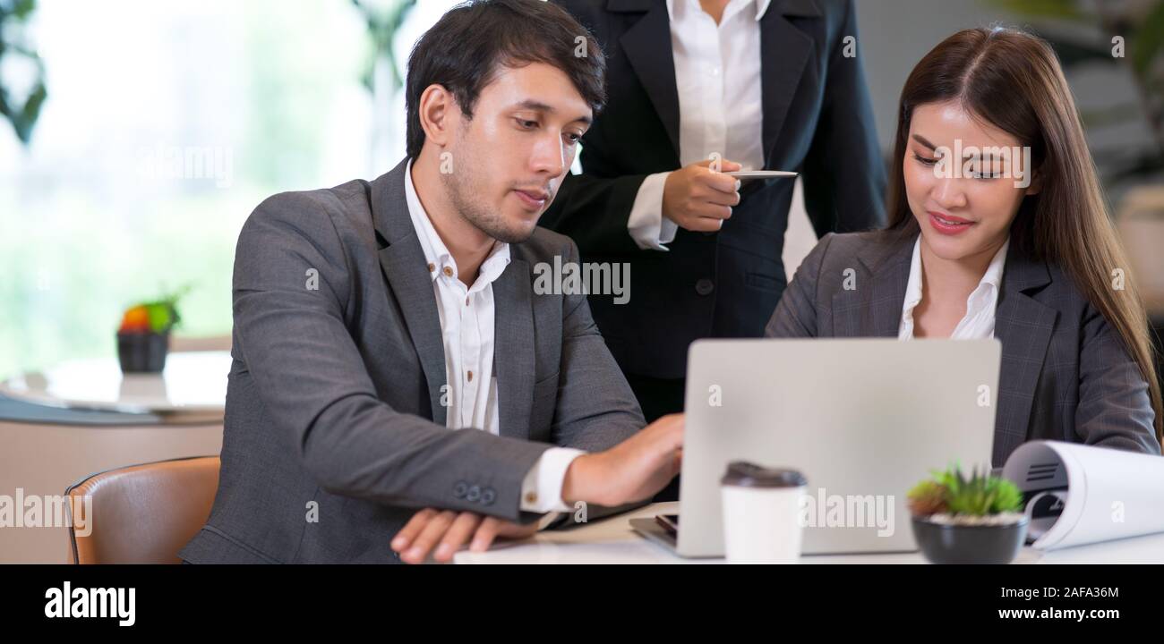 Young Asian man and business people are meeting in office discussion with colleagues . Group of Business team working and share ideas about project to Stock Photo