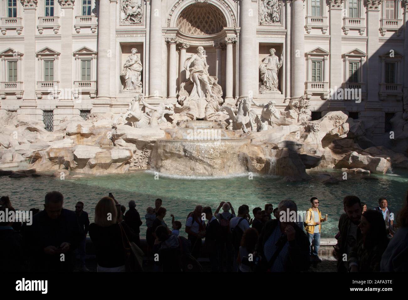 Tourists pose for pictures and to throw coins into the Trevi Fountain in Rome Stock Photo