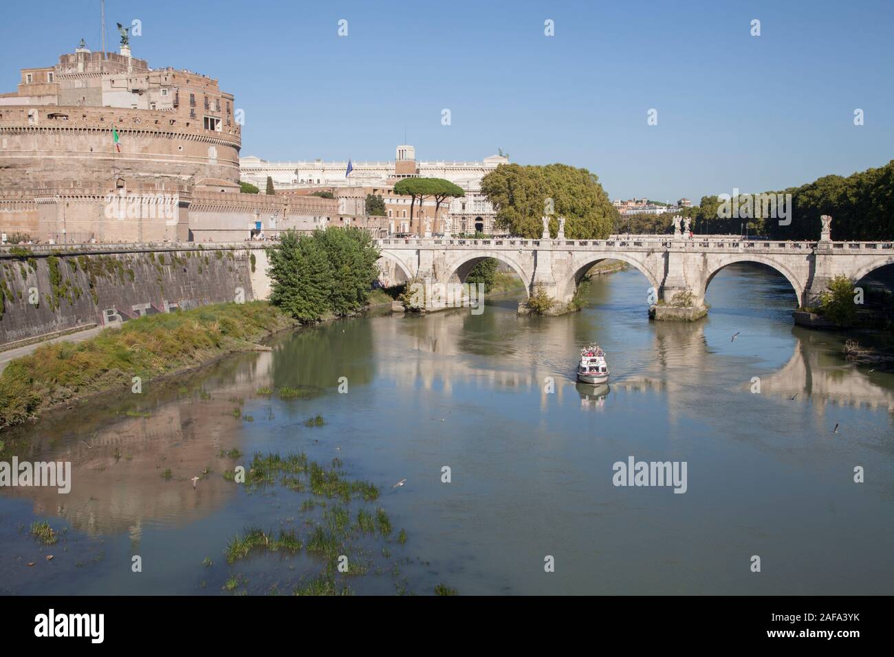A tourist boat passes under the Ponte Sant'Angelo near the Castel Sant'Angelo on the River Tiber in Rome Stock Photo
