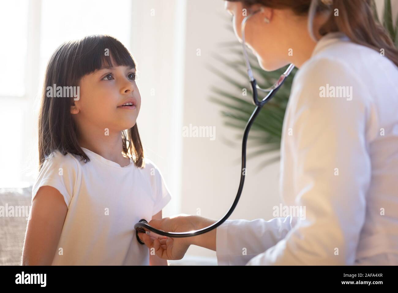 Pediatrician with stethoscope listening to lung and heart sound of